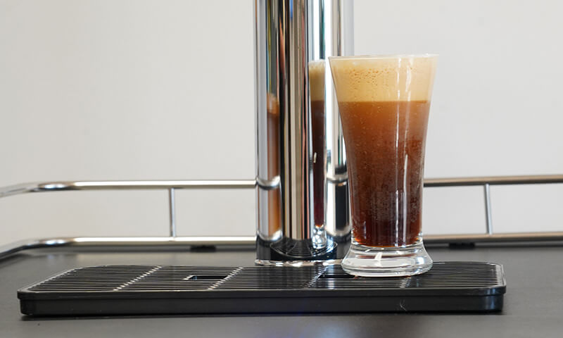 A glass of cold brew coffee sitting on a nitro cold brew kegerator